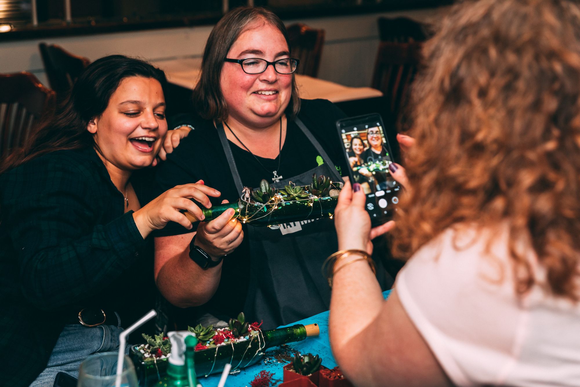 Women smiling for a photo at a work event with their Plant Nite projects