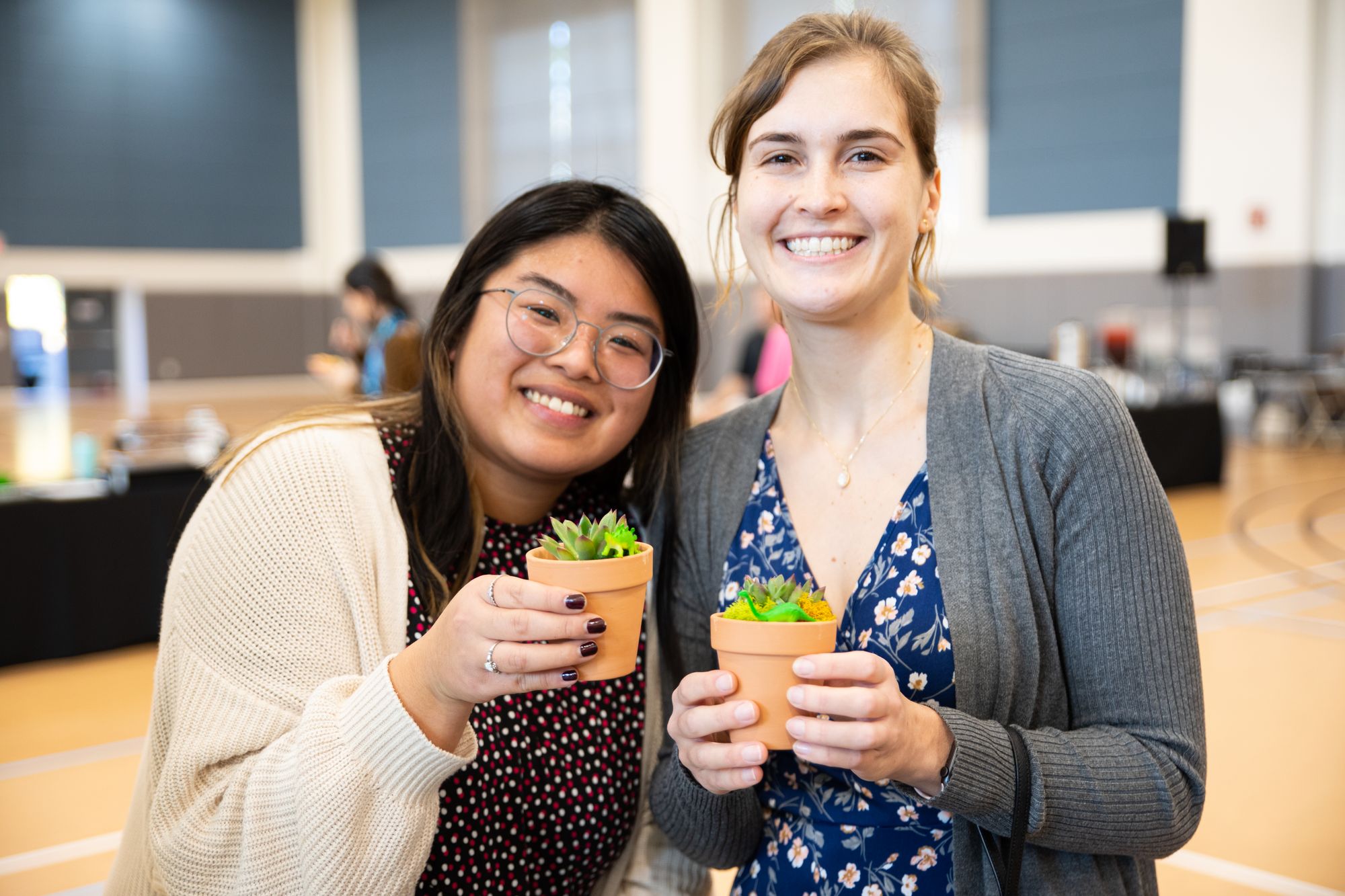 Two female coworkers holding mini succulent planters after team building event