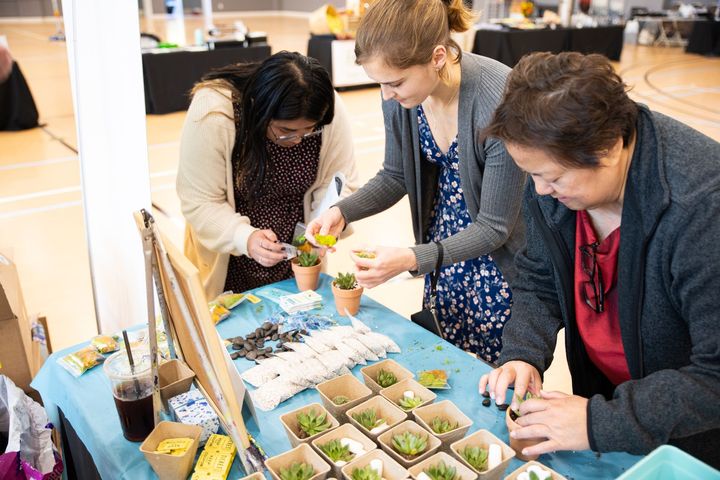 Women creating succulent planters at a Yaymaker team-building event